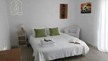 Een slaapkamer met een bed, kussens, een nachtkastje, een lamp en een schilderij aan de muur.