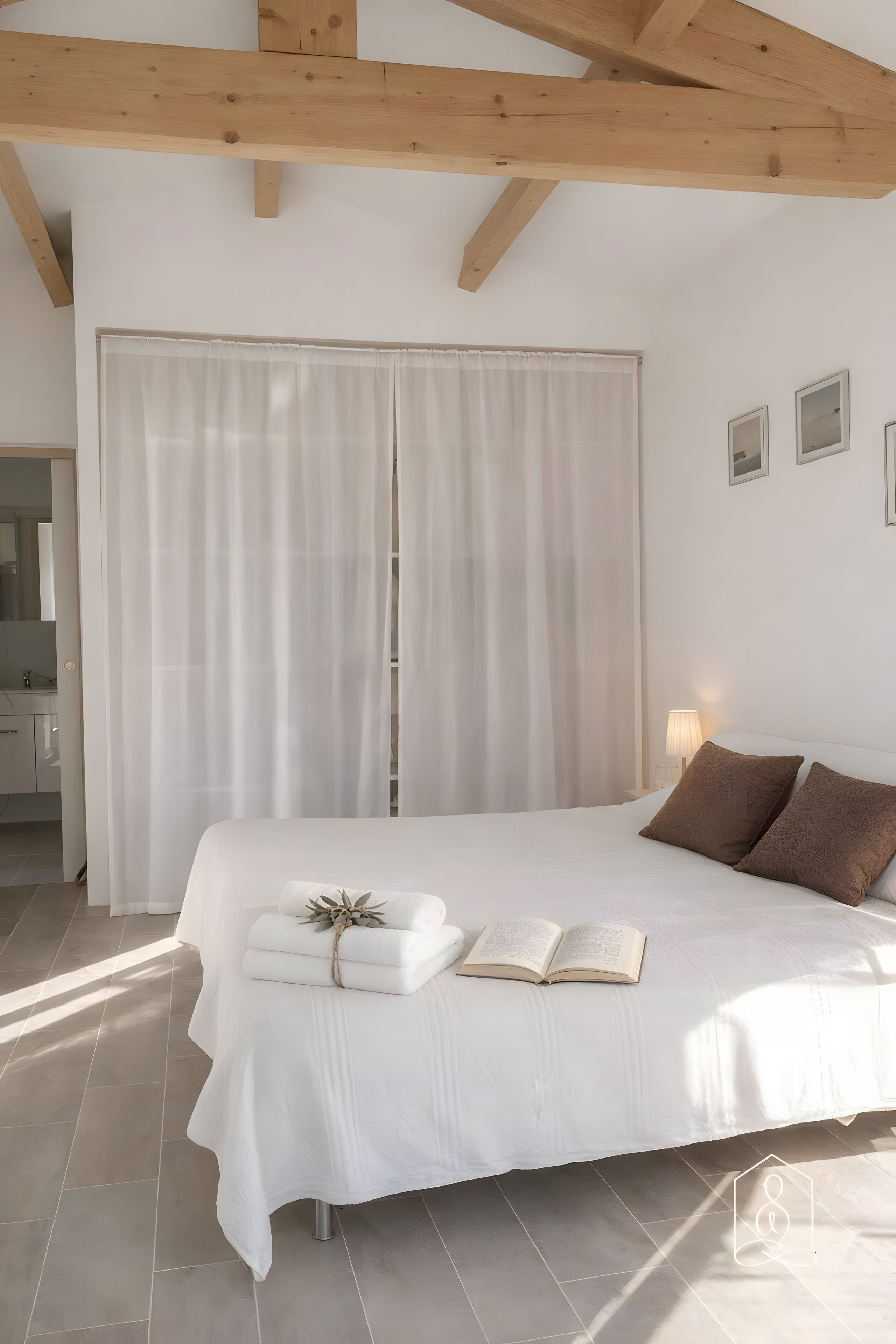 Une chambre à coucher avec un grand lit, une table de chevet et une fenêtre avec des rideaux.