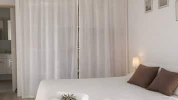 Une chambre à coucher avec un grand lit, une table de chevet et une fenêtre avec des rideaux.
