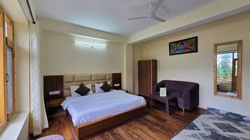A hotel room with a bed, a seating area, a wardrobe, and a ceiling fan.