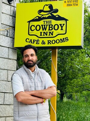 A sign for 'The Cowboy Inn' with a mountain and hat graphic, indicating a themed establishment.