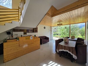 A reception area with a wooden desk, a reception sign, and a view of greenery outside. - The Cow Boy Manali (Manali)