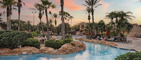 A pool area with palm trees, lounge chairs, and a building with a dome roof.