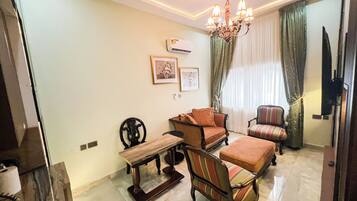 A living room with a chandelier, a sofa, a chair, a bench, and a fireplace.