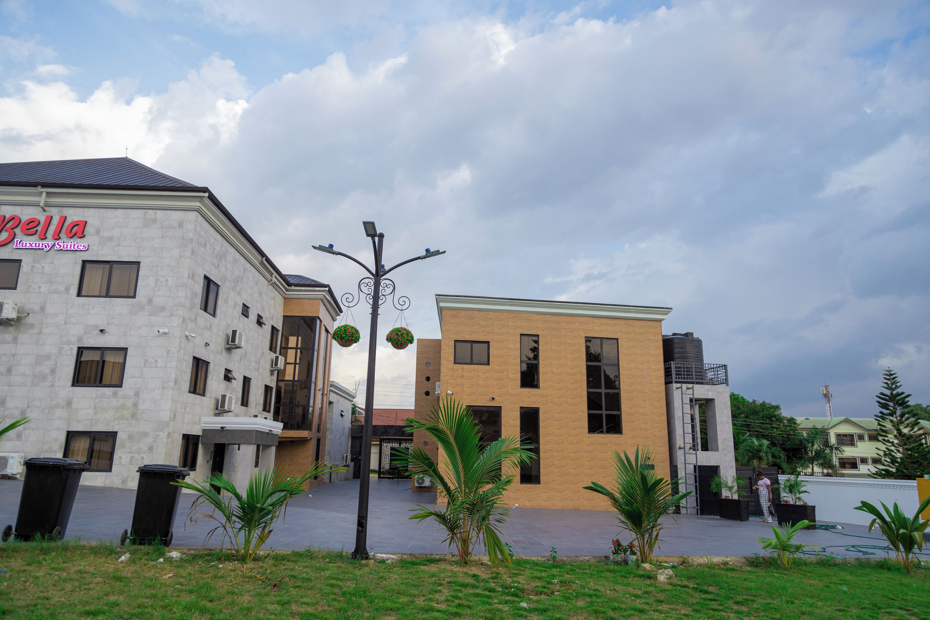 A building with a sign for 'Bella Luxury Suites' and a modern design with a flat roof and large windows.