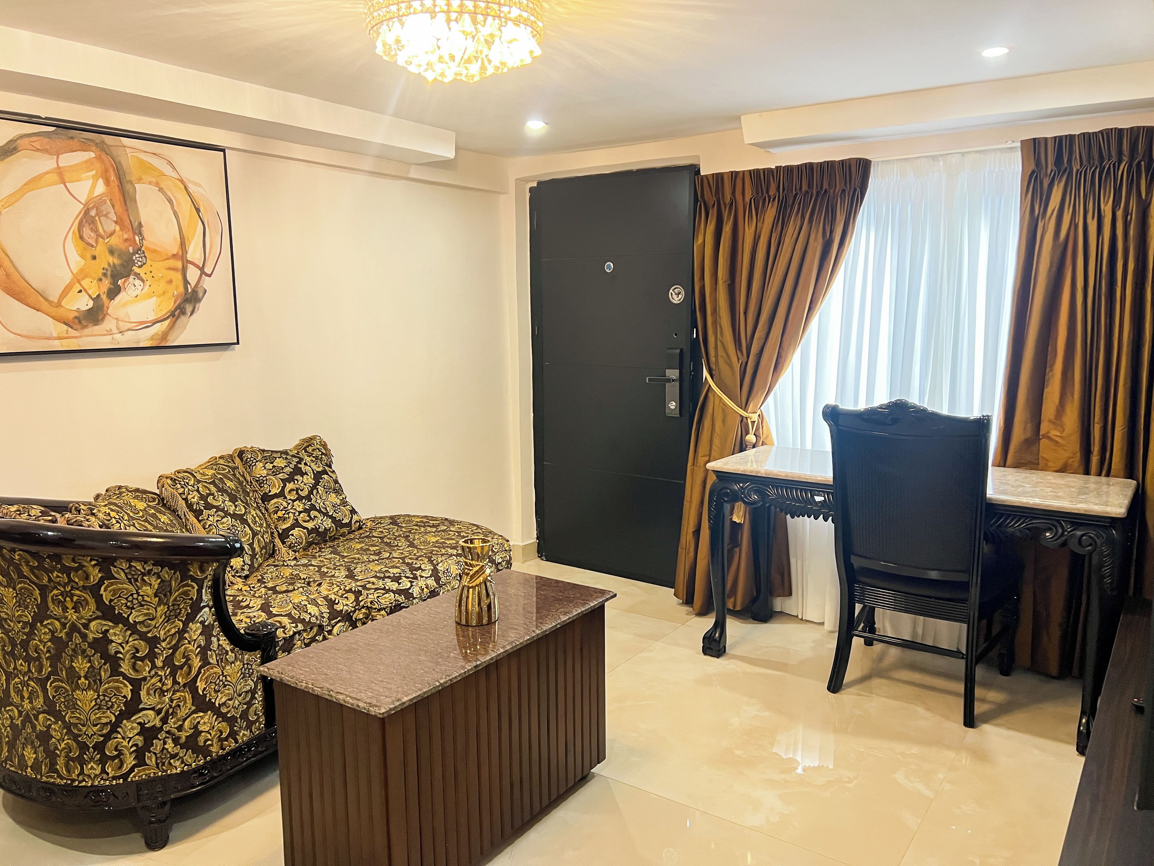 A living room with a sofa, a coffee table, a dining table with chairs, a black door, and a window with curtains.
