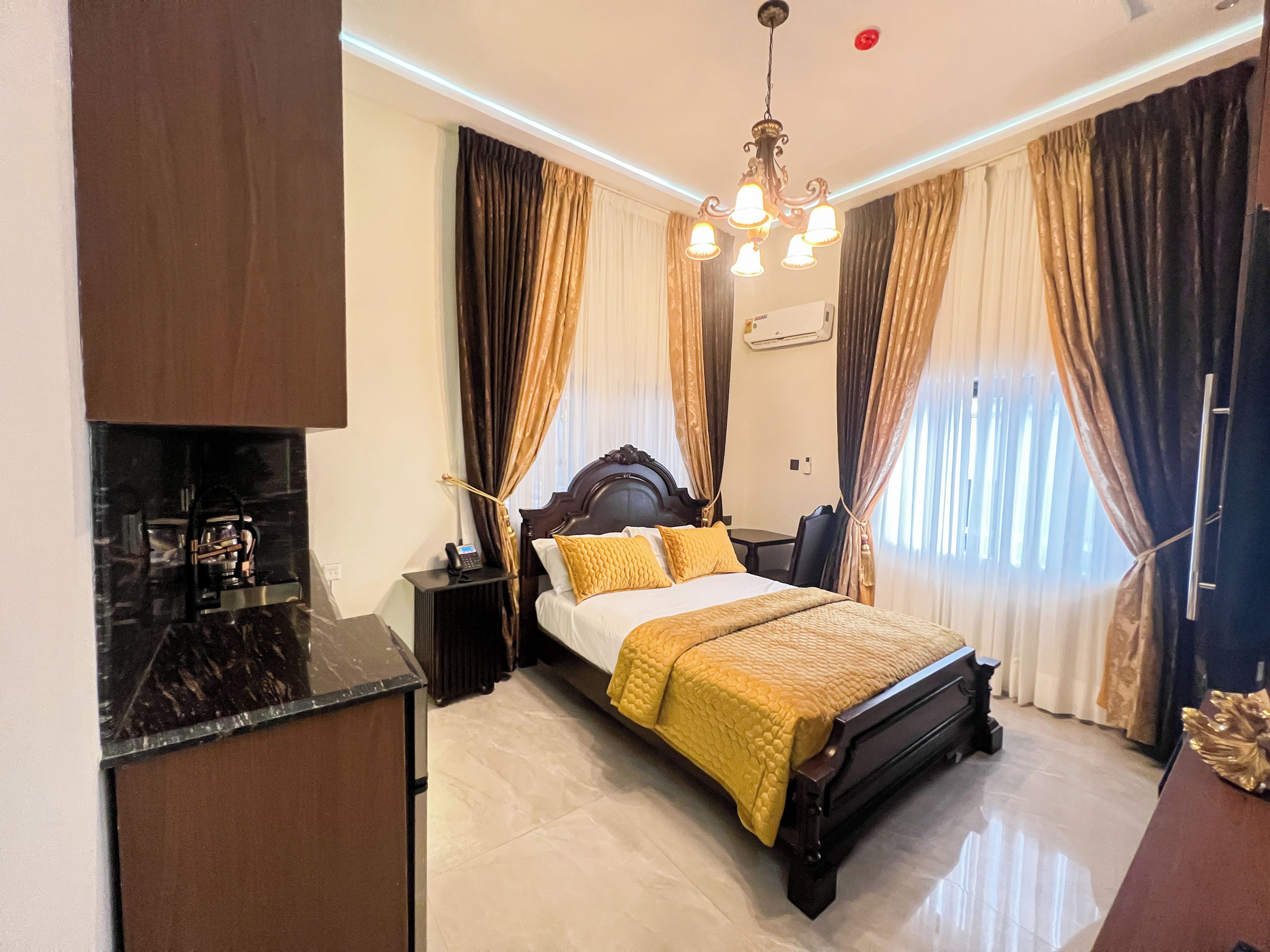 A hotel room with a bed, bedside table, and a desk with a chair.
