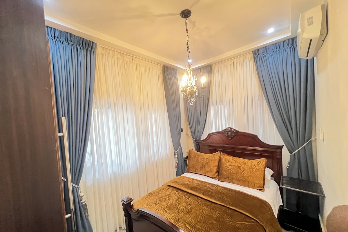 Ein Hotelzimmer mit einem Bett, Vorhängen, einer Chandelüster und einer Klimaanlage.