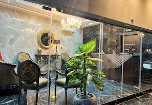 Un interior moderno con piso de mármol, una araña, un espejo redondo y una planta en maceta.