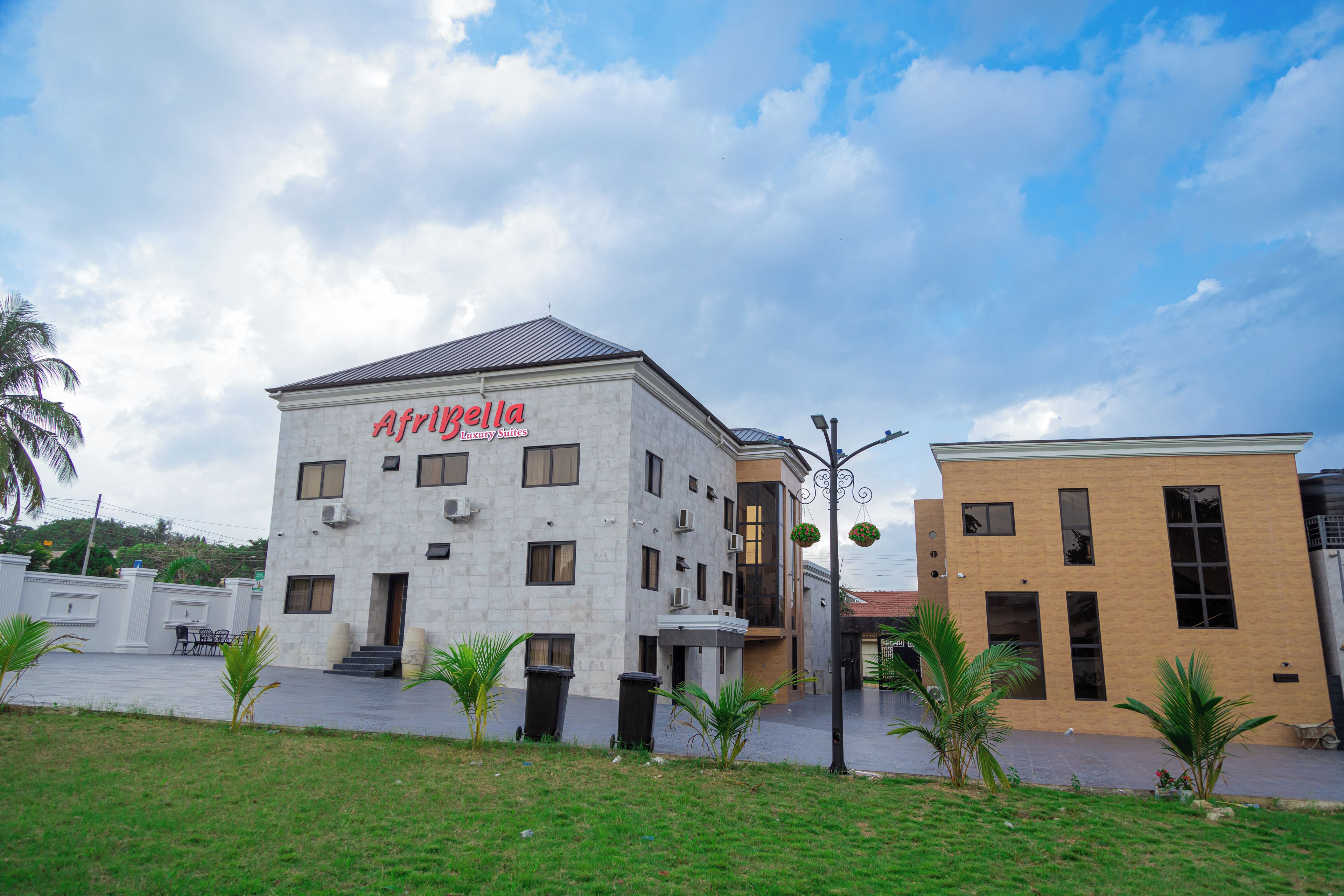Un immeuble arborant une enseigne indiquant « AfriBella Luxury Suites » et présentant un design moderne, avec de nombreuses fenêtres et un toit plat.