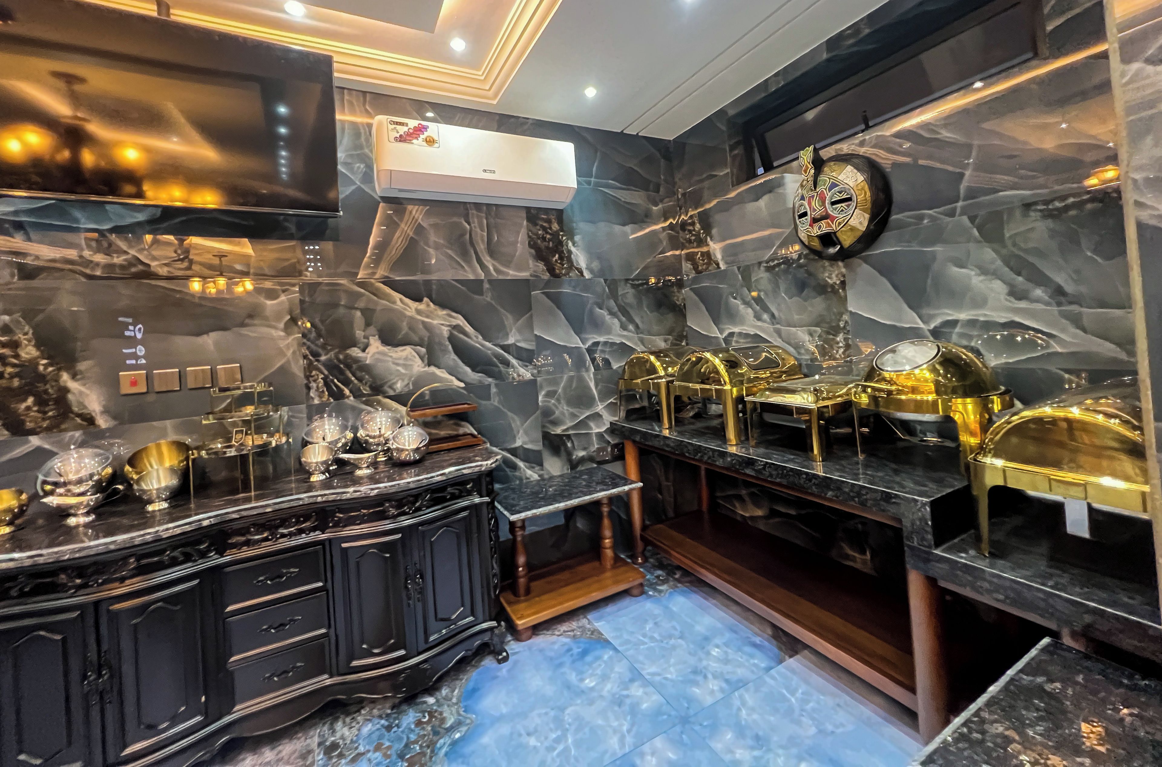 A luxurious bathroom with marble walls, gold fixtures, and a black vanity.