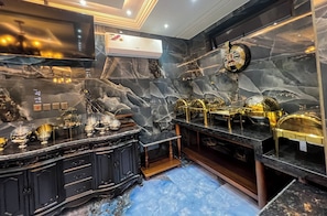 A luxurious bathroom with marble walls, gold fixtures, and a black vanity. - AfriBella Luxury Suite (Kumasi)