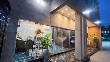 A modern hotel entrance with a glass facade, marble flooring, and a chandelier.