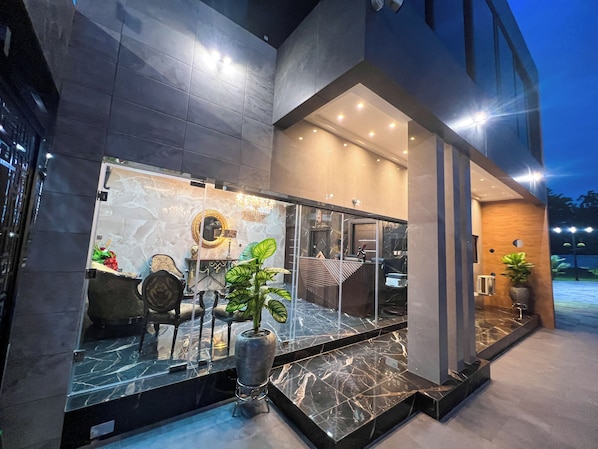 A modern hotel entrance with a glass facade, marble flooring, and a chandelier. - AfriBella Luxury Suite (Kumasi)