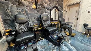 A luxurious spa room with black leather seating, a massage table, and a marble floor.