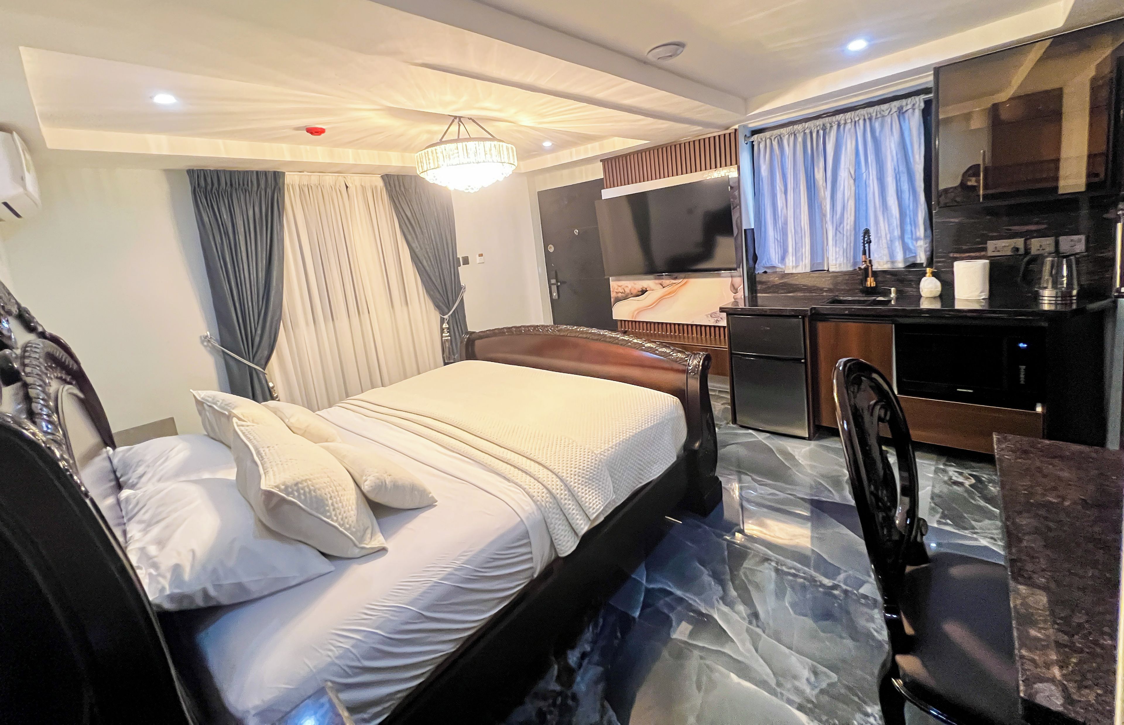 A hotel room with a bed, a desk, a chair, a television, and a bathroom.
