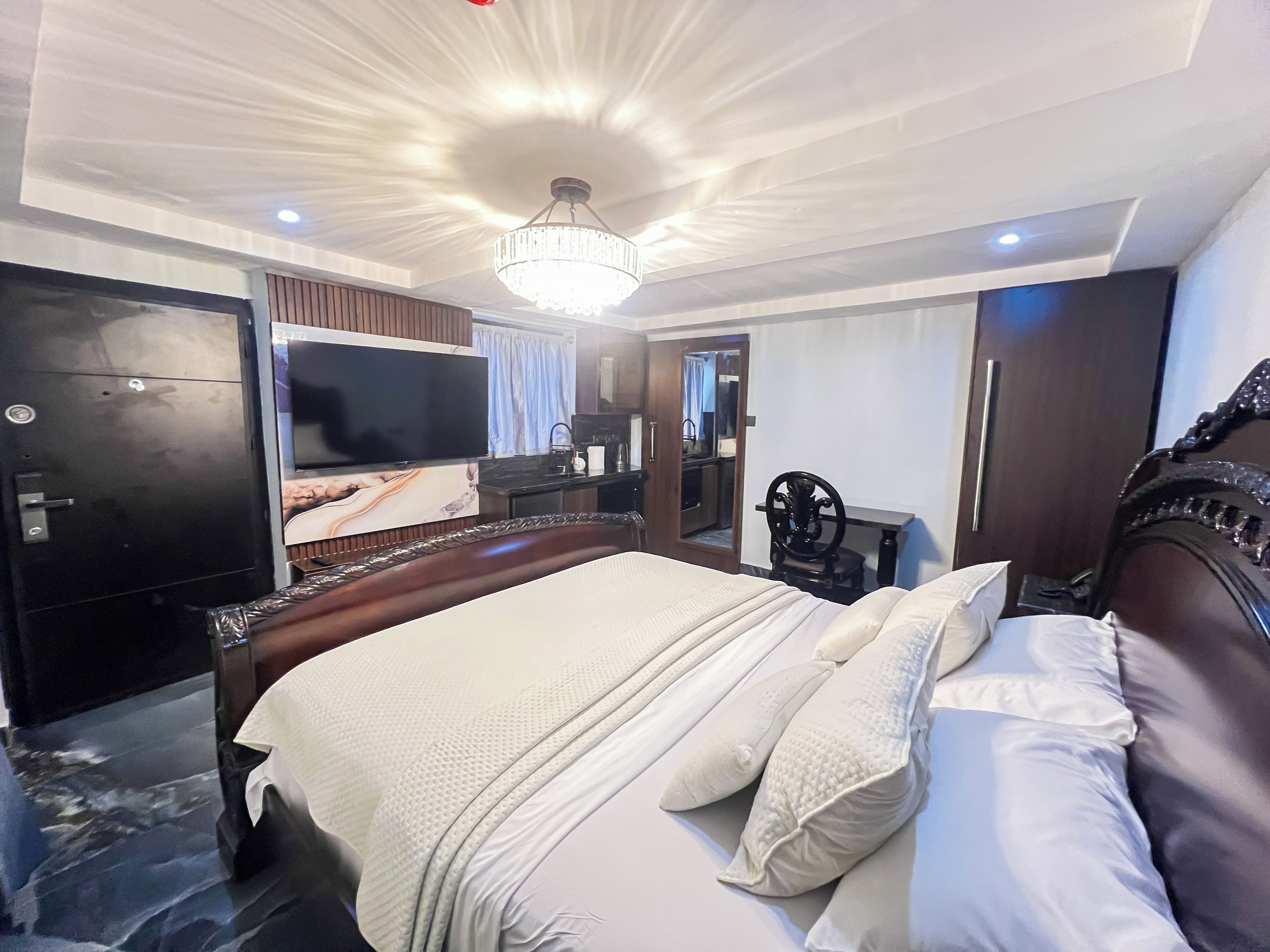 Une chambre d’hôtel avec un grand lit, une télévision, une armoire et un miroir.