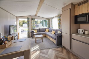 A compact living space with a sofa, coffee table, kitchenette, and a view of the outdoors. - Host & Stay | Butterfly Retreat (Northumberland)