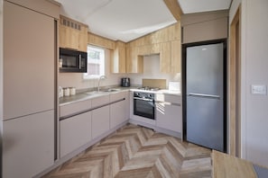 A compact kitchen with a built-in oven, a microwave, a refrigerator, and a coffee maker. - Host & Stay | Butterfly Retreat (Northumberland)