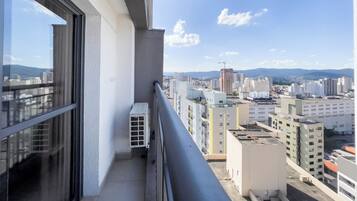 A balcony with a view of a cityscape, including buildings and mountains in the distance.