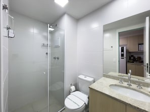 Ein modernes Badezimmer mit einer Duschkabine, einer Toilette und einem Waschbecken mit Spiegel darüber.