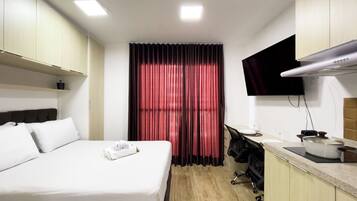 Habitación de hotel con cama, escritorio, televisor de pantalla plana y kitchenette.