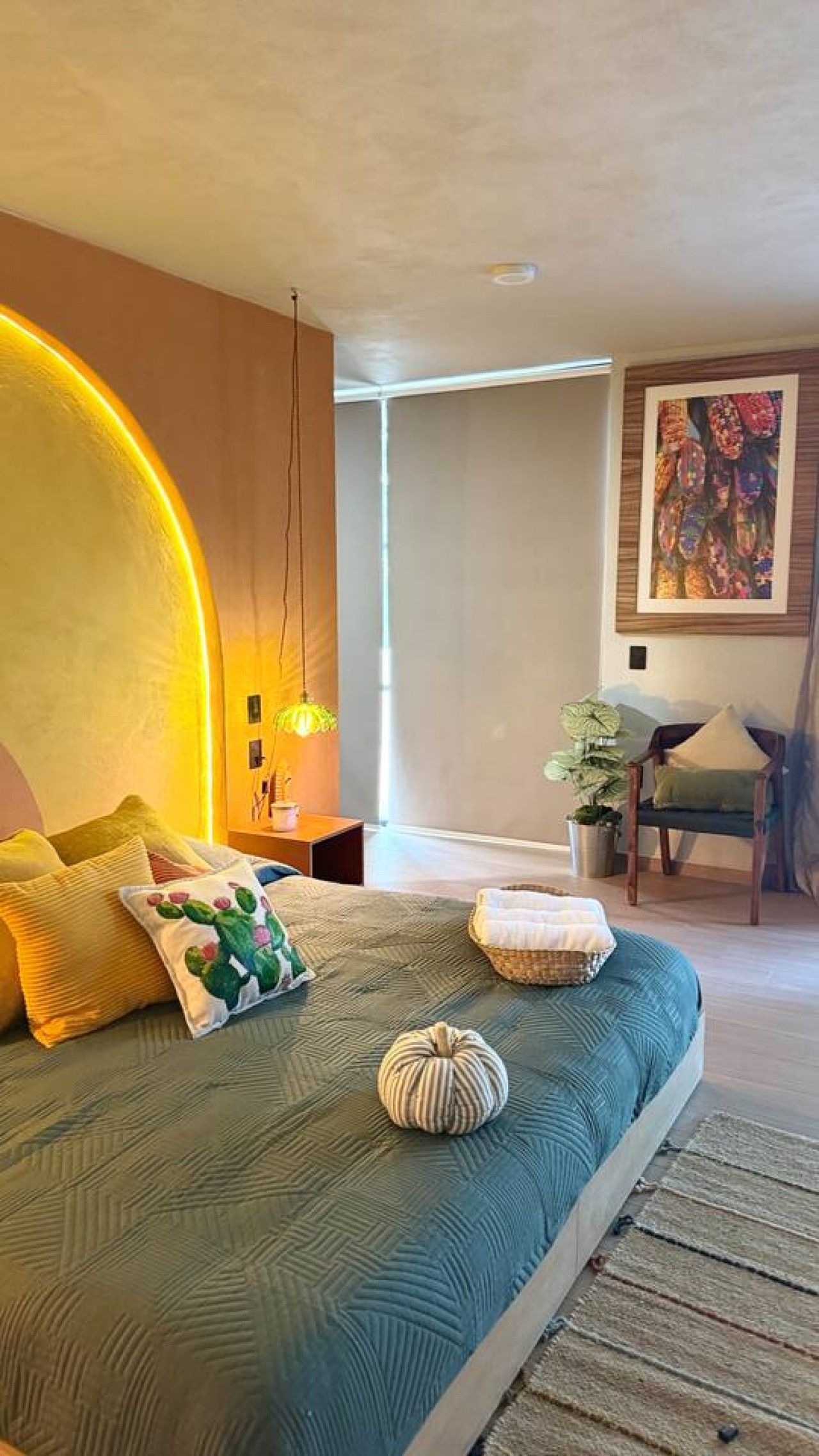 A bedroom with a bed, a nightstand, a chair, and a painting on the wall.