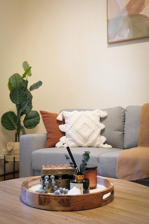 A living room with a grey sofa, a white throw blanket, and a wooden coffee table with decorative items. - Historic 4BR Edwardian Terrace | Walk to Rail (Redfern)