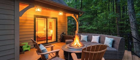 Una terraza con mobiliario exterior, una chimenea y la entrada de un edificio.