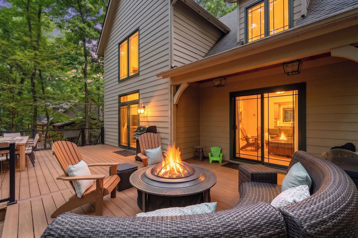 A deck with outdoor furniture, a fire pit, and a covered area with sliding glass doors.