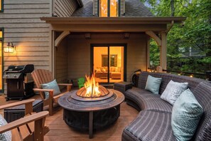 A covered outdoor seating area with a fire pit, a grill, and a sofa with cushions. - Wintergreen Resort, Hot Tub, Trails, and Ski! (Nellysford)