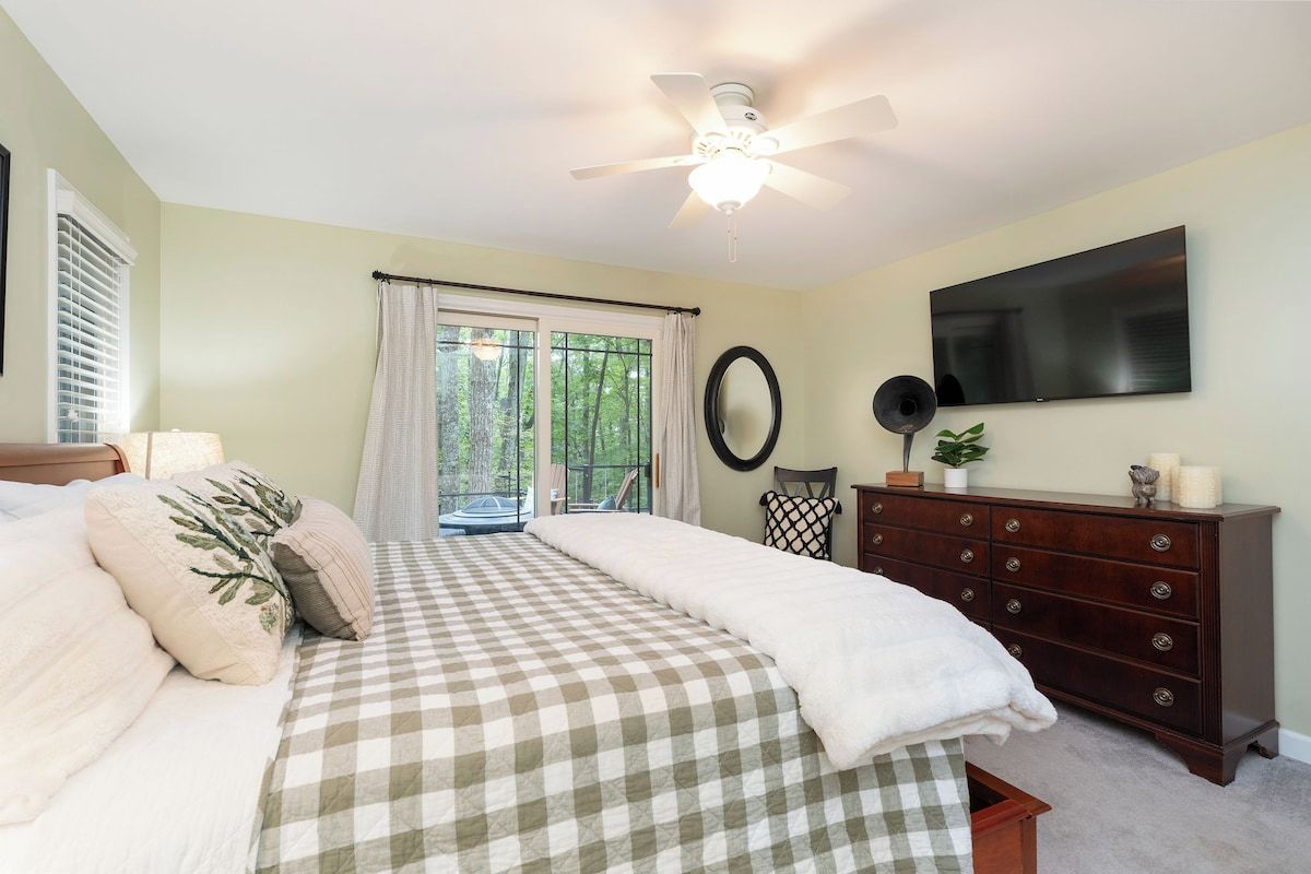 A bedroom with a bed, a dresser, a television, and a ceiling fan.