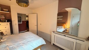 A bedroom with a bed, dresser, mirror, and a door leading to another room. - Serene 1BDR Brixton Retreat with Private Patio (Greater London)