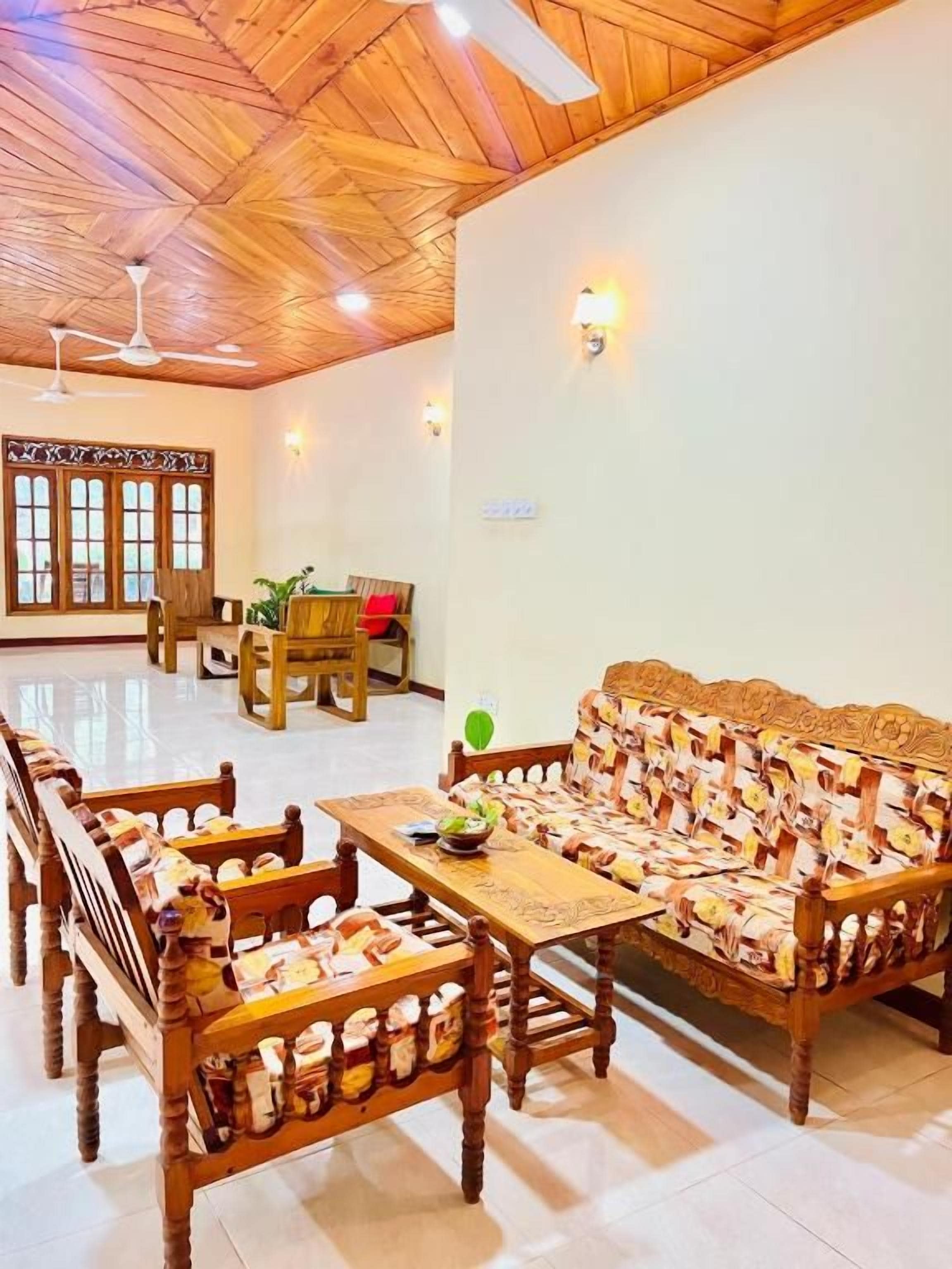 A spacious room with a wooden ceiling, a sofa set, a dining table, and a window with multiple panes.