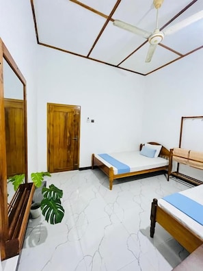 Un dormitorio con una cama, ventilador de techo, puerta de madera y planta en maceta.
