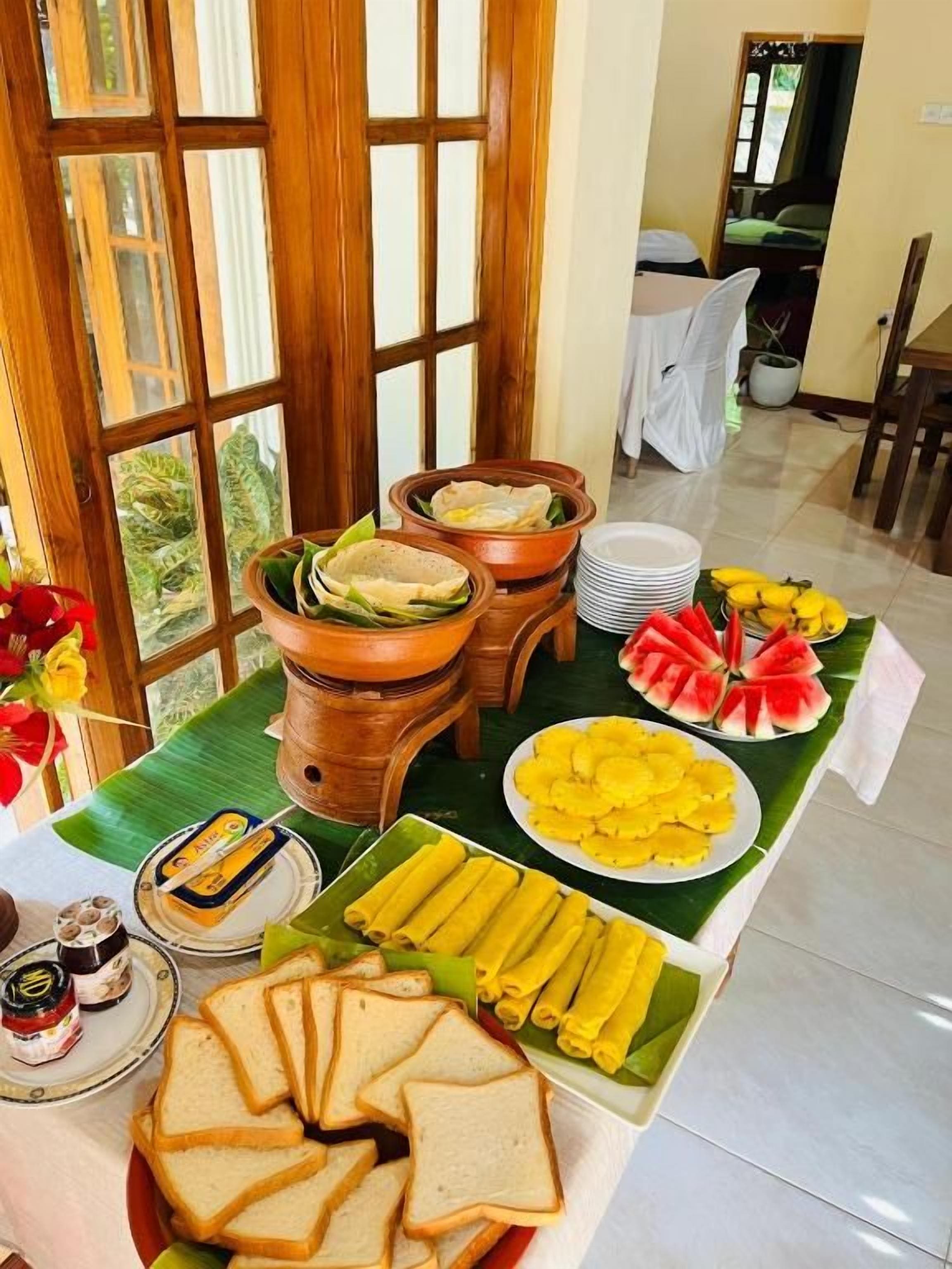 A buffet table with various food items including bread, fruits, and condiments.