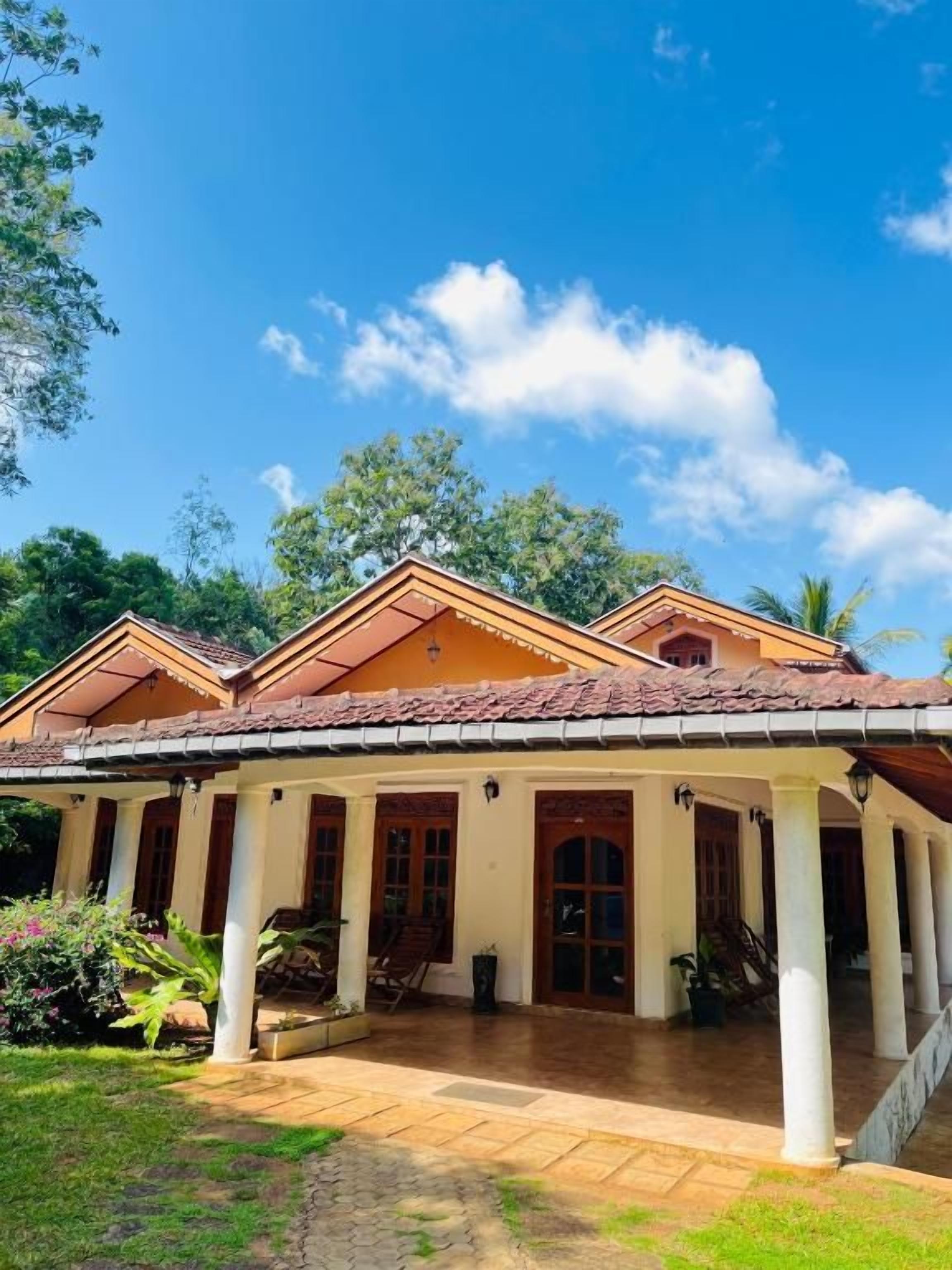 A two-story building with a covered patio area, columns, and a tiled roof.