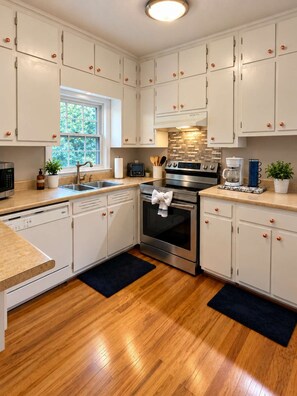 A kitchen with white cabinets, stainless steel appliances, a window, and a potted plant. - Budget-Friendly Smyrna Retreat Near Braves (Smyrna)