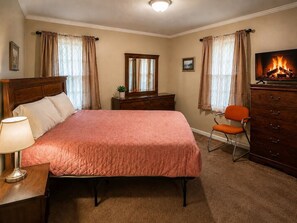 A bedroom with a bed, a dresser, a chair, a lamp, and a fireplace. - Budget-Friendly Smyrna Retreat Near Braves (Smyrna)