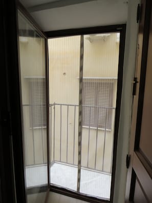 Una habitació amb una porta corredissa de vidre que dona a un balcó amb barana metàl·lica.