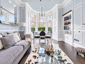 A spacious living room with a large window, a dining area with a glass table, and a modern sofa. - Charming 3BR - Stockbridge & Botanic Garden (Edinburgh)