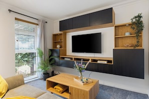 A modern living room with a flat-screen TV, built-in shelves, a coffee table, and a sofa. - The Hideaway - Perfect for professionals, contractors and leisure guests (Ash Vale)