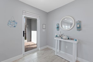A room with a white console table, a round mirror, and a welcome sign. - Beachside Oasis 🌴 Canal Front 4BR Home | Private Pool + Spillover Spa (Fort Myers Beach)