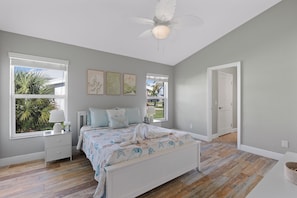 A bedroom with a bed, a nightstand, a window with blinds, a ceiling fan, and artwork on the wall. - Canal Paradise Retreat 🌴⛵ Dock + Heated Pool | Near Times Square (Fort Myers Beach)