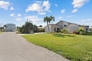 A residential street with houses, a clear sky, and a well-maintained lawn. - Canal Paradise Retreat 🌴⛵ Dock + Heated Pool | Near Times Square (Fort Myers Beach)