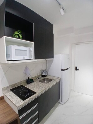 A kitchen with a microwave, sink, and refrigerator. - SETIN 302 (São Paulo)