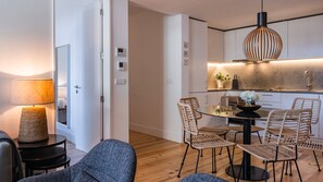 A modern kitchen with a dining area, featuring a round glass table, wicker chairs, and a pendant light. - Design 2BR Duplex with AC by LovelyStay (Lisboa)
