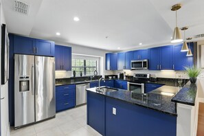Een moderne keuken met blauwe kastjes, roestvrijstalen apparatuur en een granieten aanrecht.