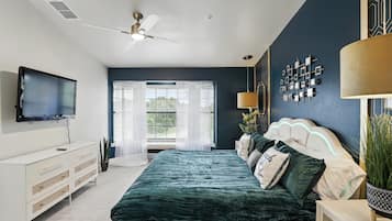 A bedroom with a bed, a TV, a ceiling fan, and a window with blinds.