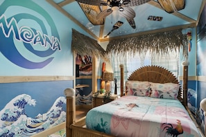 Una habitación con un cuadro tradicional japonés de olas, una cama con un colcha colorida y un ventilador de techo.